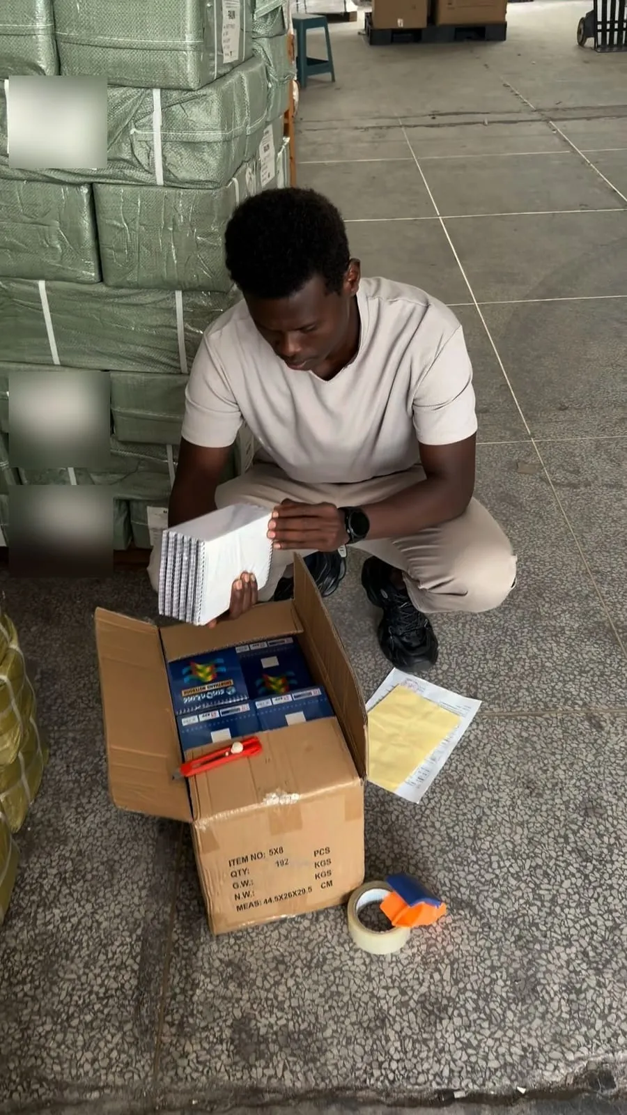 Abdulhakim Ali Hassan oo sanduuqyada alaabta furaya oo tirada iyo tayada hubinaya bakhaarka Shiinaha